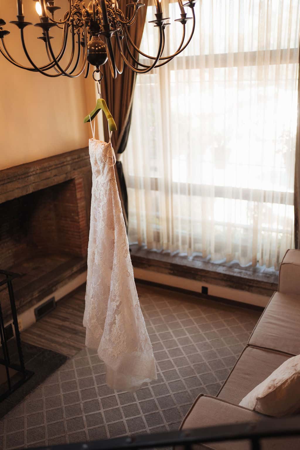 Bridal gown hanging from the chandelier next to the fireplace in the Bride's House