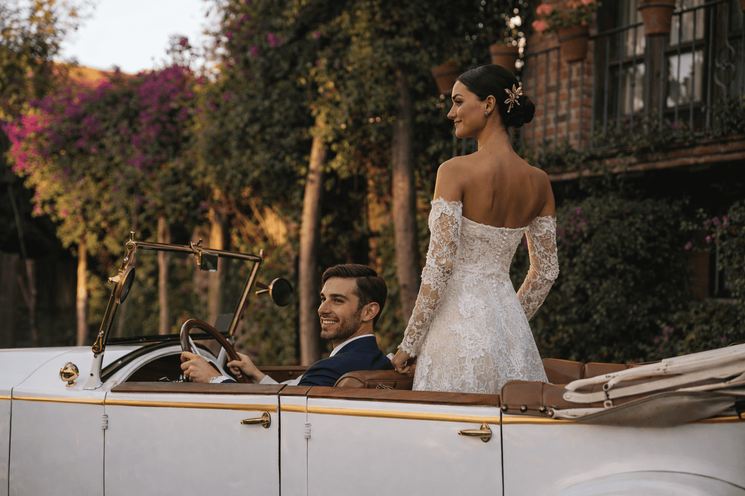 Bride and groom in classic car at dusk in front of the hacienda