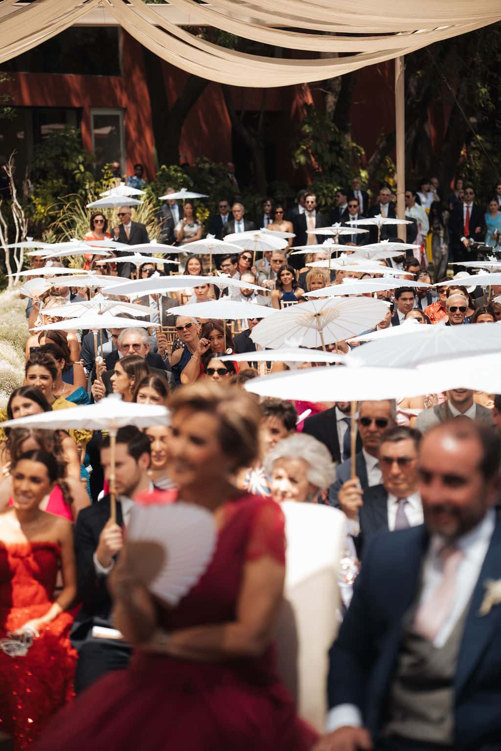 Guests with umbrellas during the ceremony in the garden